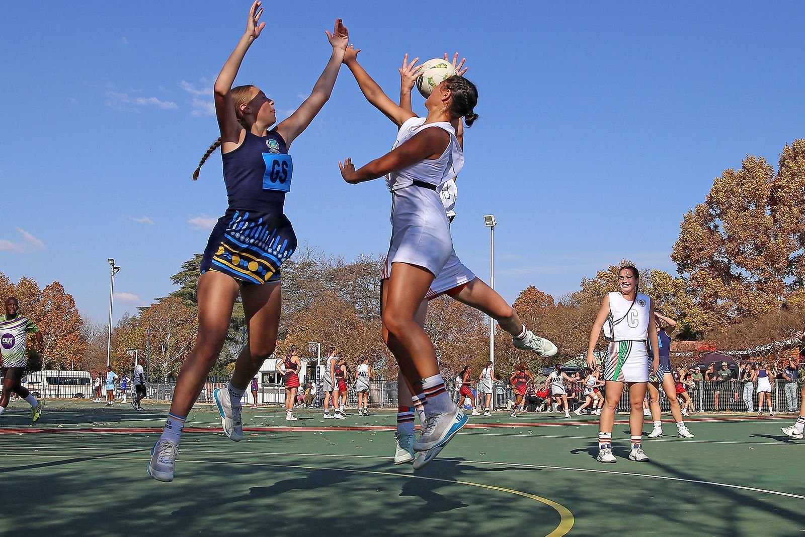Players competing for the ball in an energetic outdoor netball match